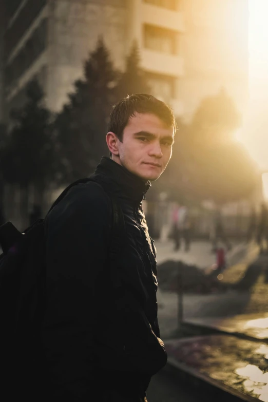 a man stands in front of some buildings at sunset