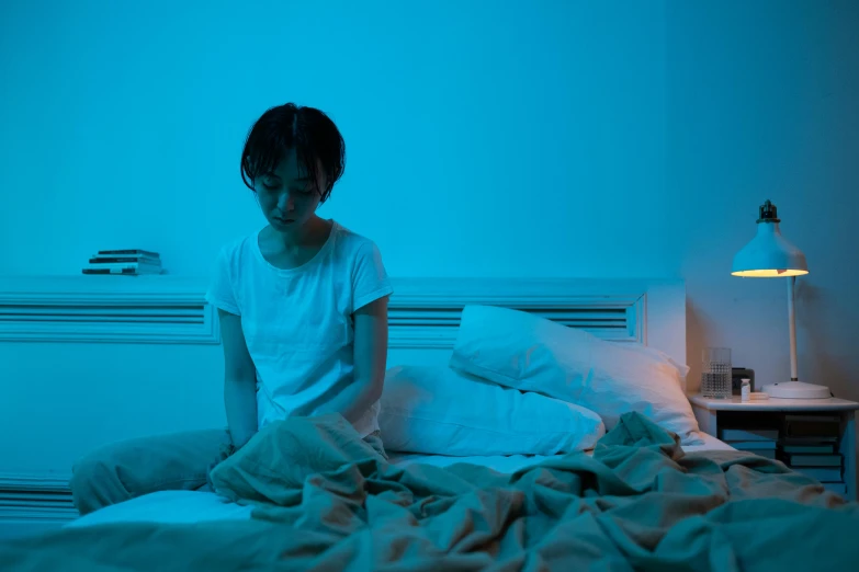 a woman is sitting on her bed in the dark