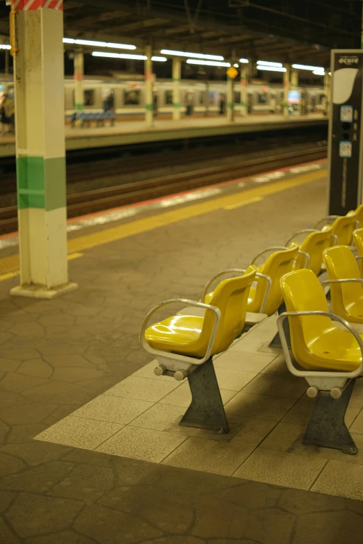 a group of yellow chairs sitting on top of a train platform