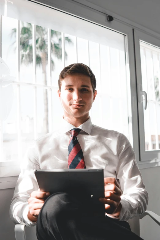 a man is wearing a tie sitting down looking at his laptop