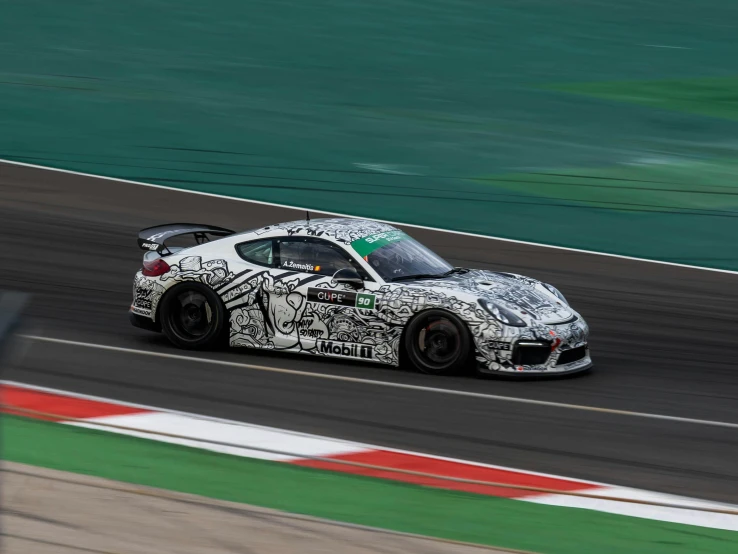 a white and black sports car driving on a race track