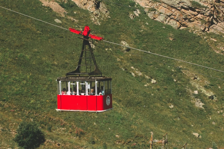 a red cable car sitting on top of green grass