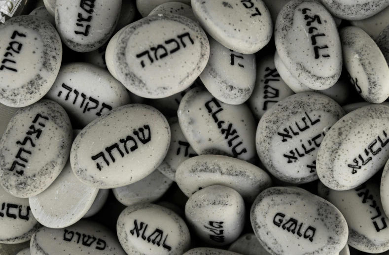 a pile of white rocks with black writing on them, by Siona Shimshi, pexels, hebrew, glass beads clay amulets, | 35mm|, dark and white