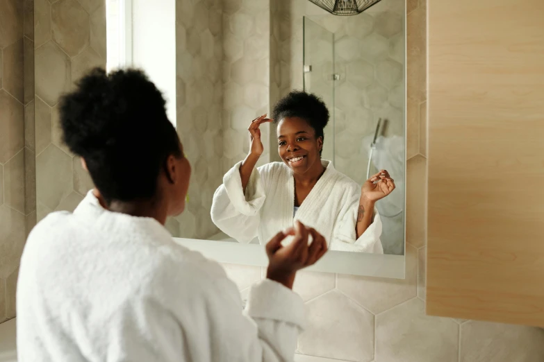 woman in robe brushing her teeth in front of mirror