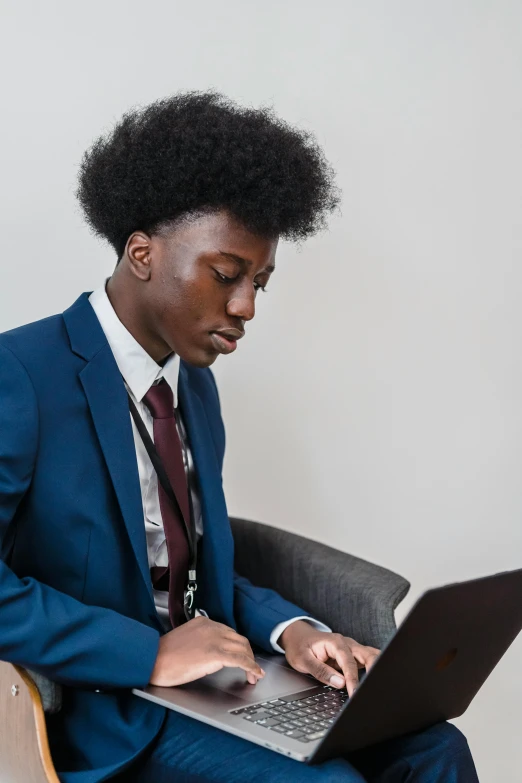 a man sitting in a chair using a laptop, trending on pexels, macron with afro hair, academic clothing, formal attire, thumbnail