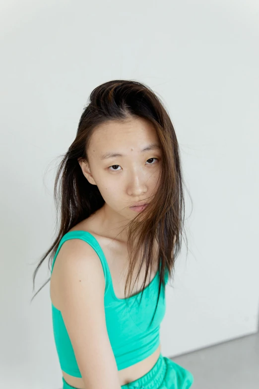 a woman in a green dress posing for a picture, inspired by Fei Danxu, hyperrealism, wearing a tanktop, frowning expression, she is about 1 6 years old, high resolution photo