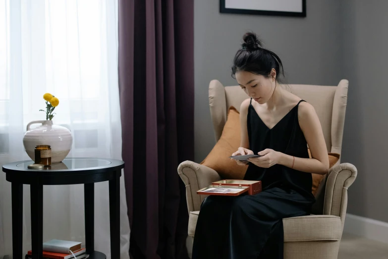 a woman sitting in a chair while looking at her phone