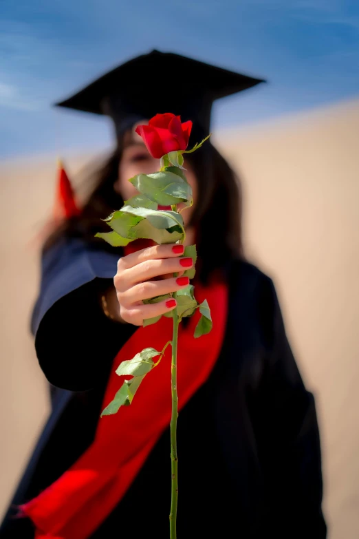 a woman wearing a cap holding a red rose