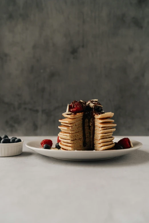 a stack of pancakes sitting on top of a white plate, unsplash, textured base ; product photos, berries, chocolate, 3 / 4 wide shot