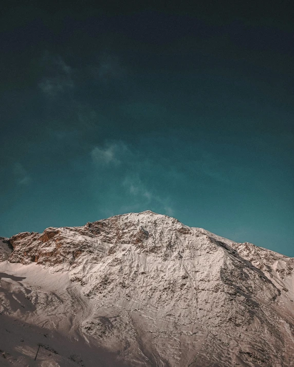 the top of a snowy mountain under a clear sky