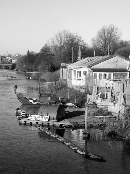 a black and white photo of a boat in the water, a black and white photo, by Tony Tuckson, process art, building along a river, barnet, mami wata, dingy gym