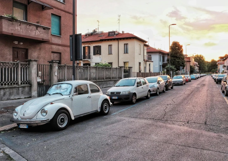 a row of cars parked on the side of a road, by Alessandro Allori, pexels contest winner, hyperrealism, beetle, filtered evening light, old cmputers on the sidewalk, white