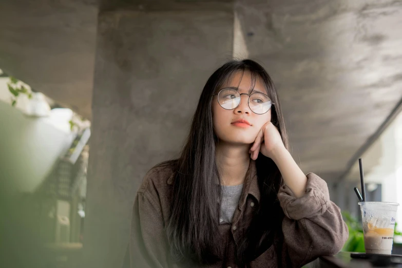 a woman sitting at a table with a cell phone to her ear, a picture, inspired by Ruth Jên, trending on pexels, realism, square rimmed glasses, asian girl with long hair, thoughtful ), high quality photo