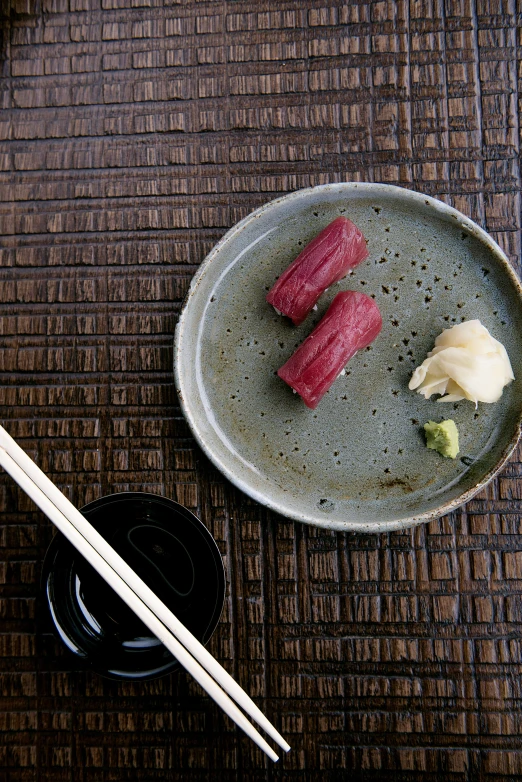 a plate of sushi and chopsticks on a table, inspired by Nishida Shun'ei, mingei, maroon, beef, square, blue