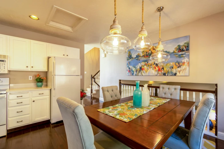 an open kitchen with two chandeliers hanging above the dining table