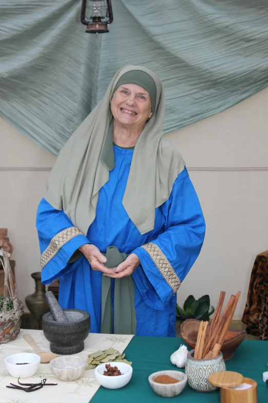 a woman that is standing in front of a table, inspired by Mary Abbott, renaissance, holy ceremony, wearing an old tunic, clay, roman festival backdrop