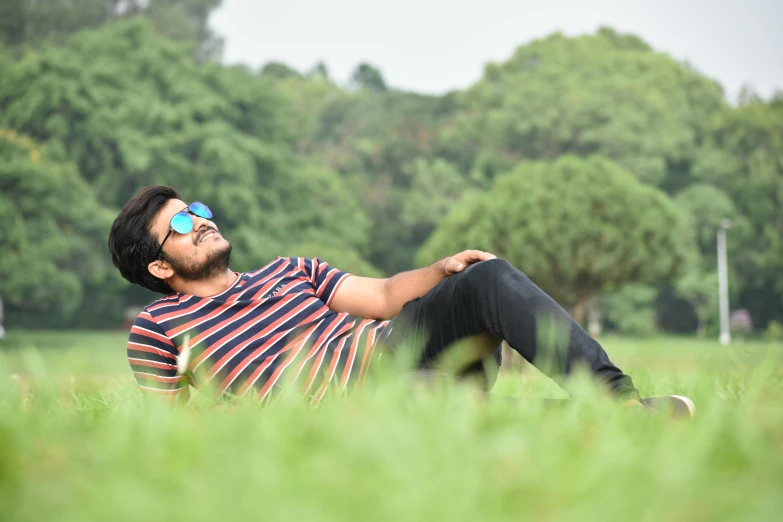 a man laying on top of a lush green field, a picture, by Thota Vaikuntham, pexels contest winner, realism, casual pose, college, today\'s featured photograph 4k, in the park