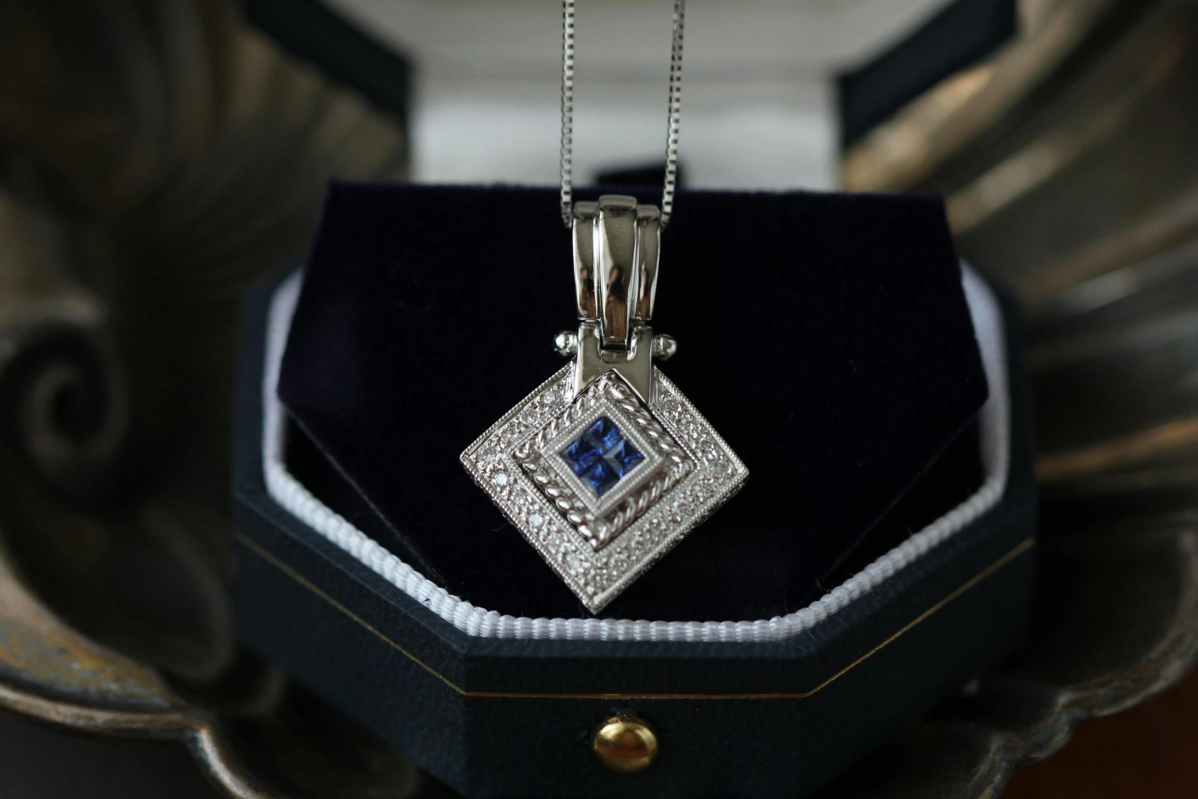 a close up of a necklace in a box, a portrait, unsplash, renaissance, silver and sapphire, square, with a square, medium close - up