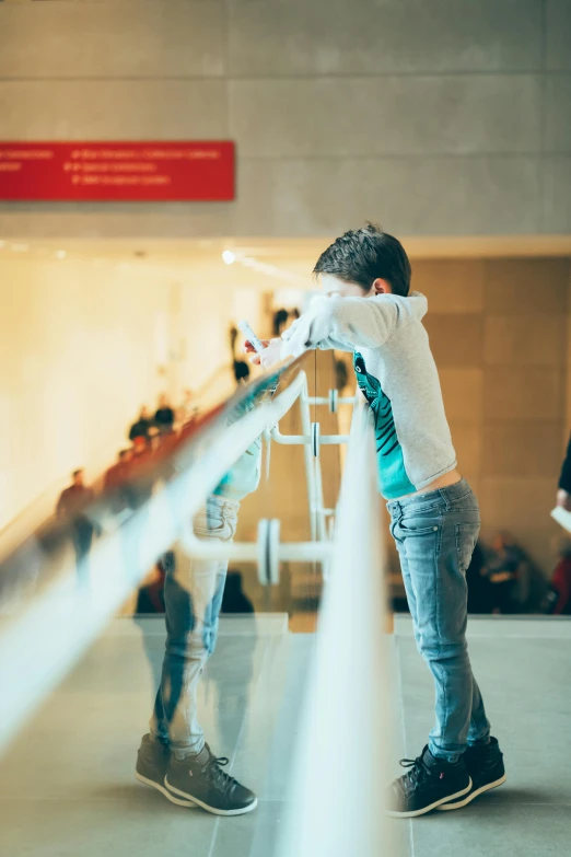 a man leaning on a railing in an airport, pexels contest winner, interactive art, young boy, museum curator, bending over, in a mall