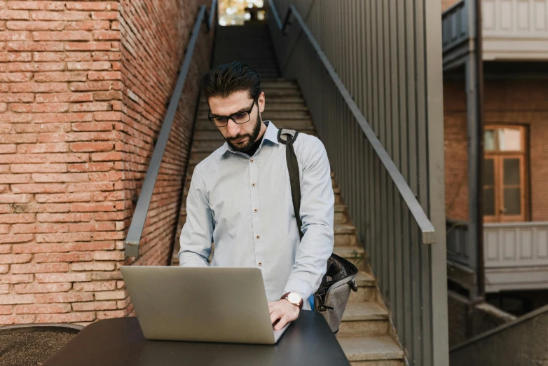 a man sitting at a table with a laptop, pexels contest winner, coming down the stairs, bearded and built, avatar image, standing posture