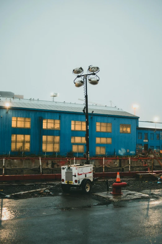 a truck parked in front of a blue building, a portrait, unsplash, industrial lighting, overcast, construction yard, searchlights