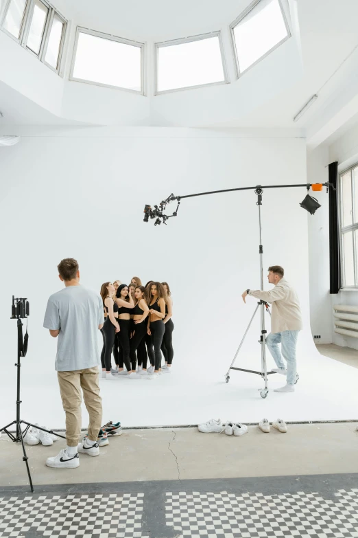 a group of people that are standing in a room, by Nina Hamnett, trending on unsplash, arbeitsrat für kunst, softbox studio lighting, white studio background, performing a music video, at a fashion shoot