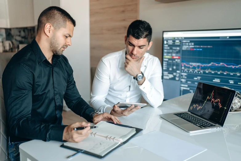 two men are looking at information on a table