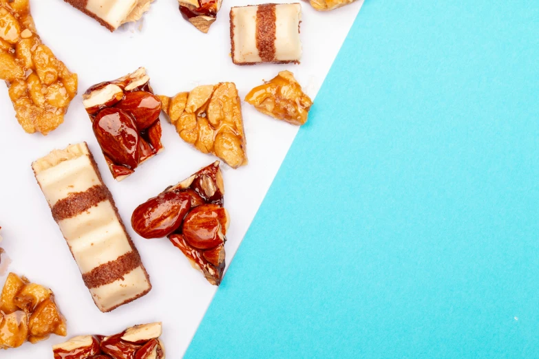 a variety of desserts sitting on top of a blue and white surface, an album cover, trending on pexels, chocolate candy bar packaging, background image, nut, geometric