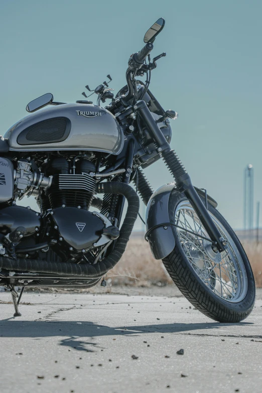 a motorcycle parked on the side of the road, a stipple, by Tom Bonson, pexels contest winner, photorealism, triumph, gunmetal grey, restomod, on the desert