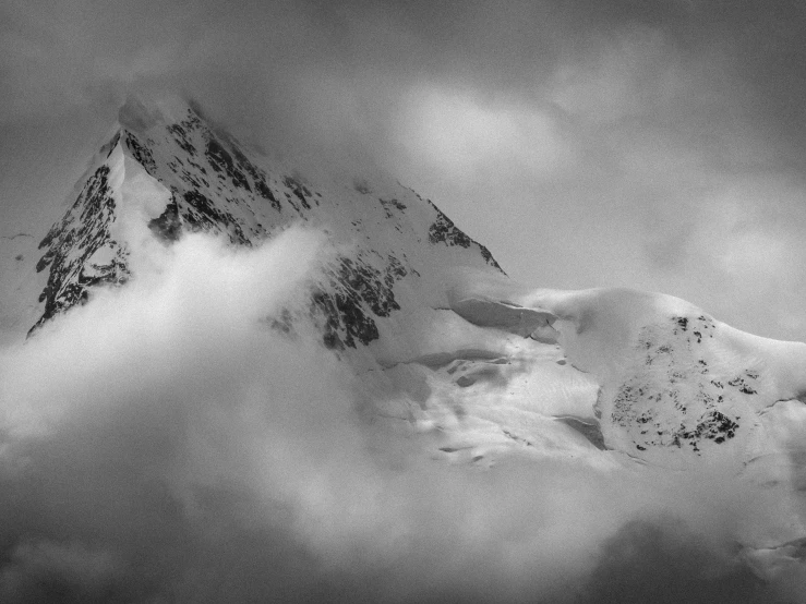 a snowy mountain under some clouds in a black and white po