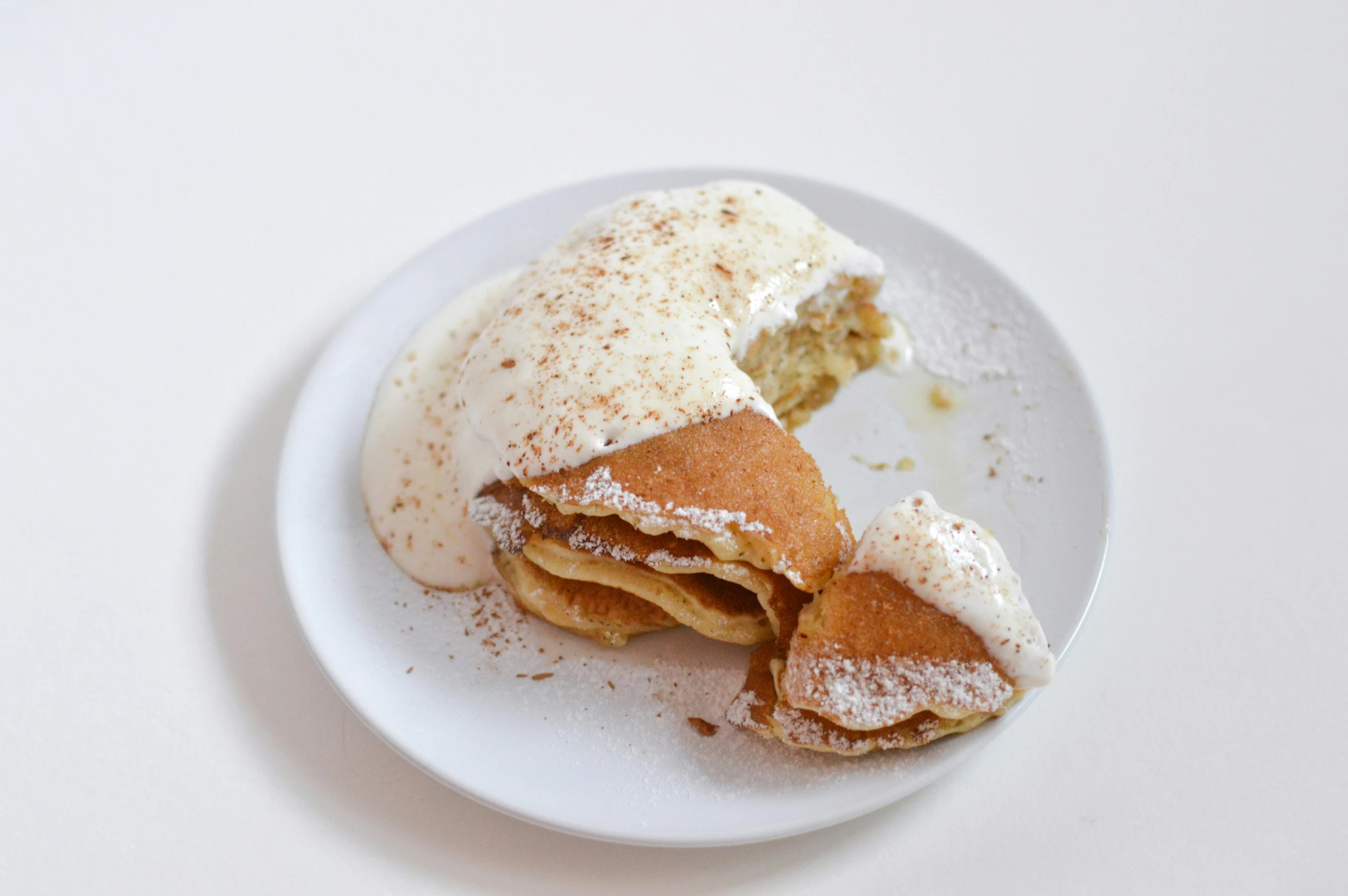 a close up of a plate of food on a table, whipped cream, flat pancake head, covered in white flour, on a white table