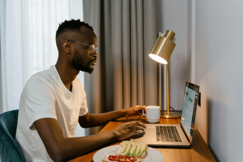 a man sitting at a desk in front of a laptop, pexels contest winner, dinner is served, jaylen brown, profile image, male with halo