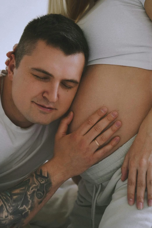 a man sitting next to a pregnant woman on a bed, profile image, tattooed, close - up photograph, white male