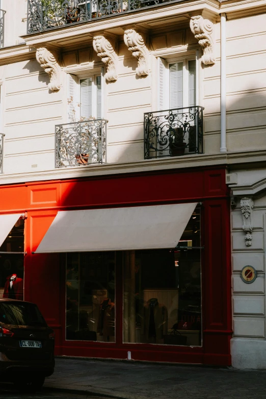 a car is parked in front of a store, by Raphaël Collin, pexels contest winner, art nouveau, red cape, cute bakery shop, late afternoon light, gif