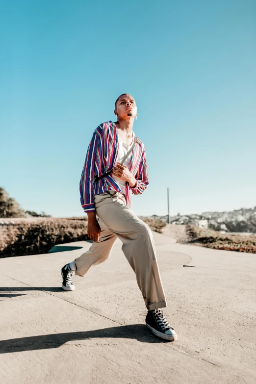 a man riding a skateboard down a street, trending on unsplash, happening, non binary model, stripey pants, standing on rocky ground, professional modeling