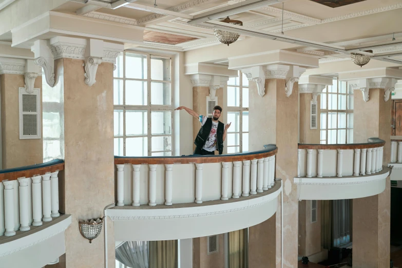 man in black jacket leaning on railing with balcony