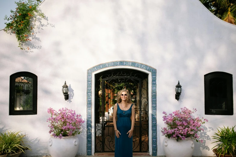 a woman standing outside a white home with windows