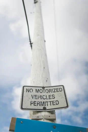 a no motorized vehicles sign attached to a wooden post