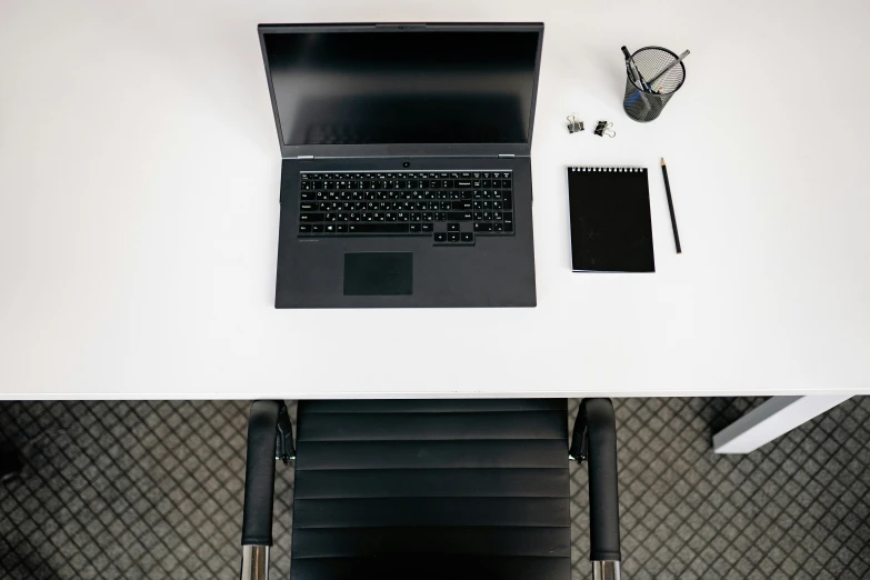 a laptop computer sitting on top of a white desk, unsplash, 9 9 designs, black chair, high - angle view, completely empty