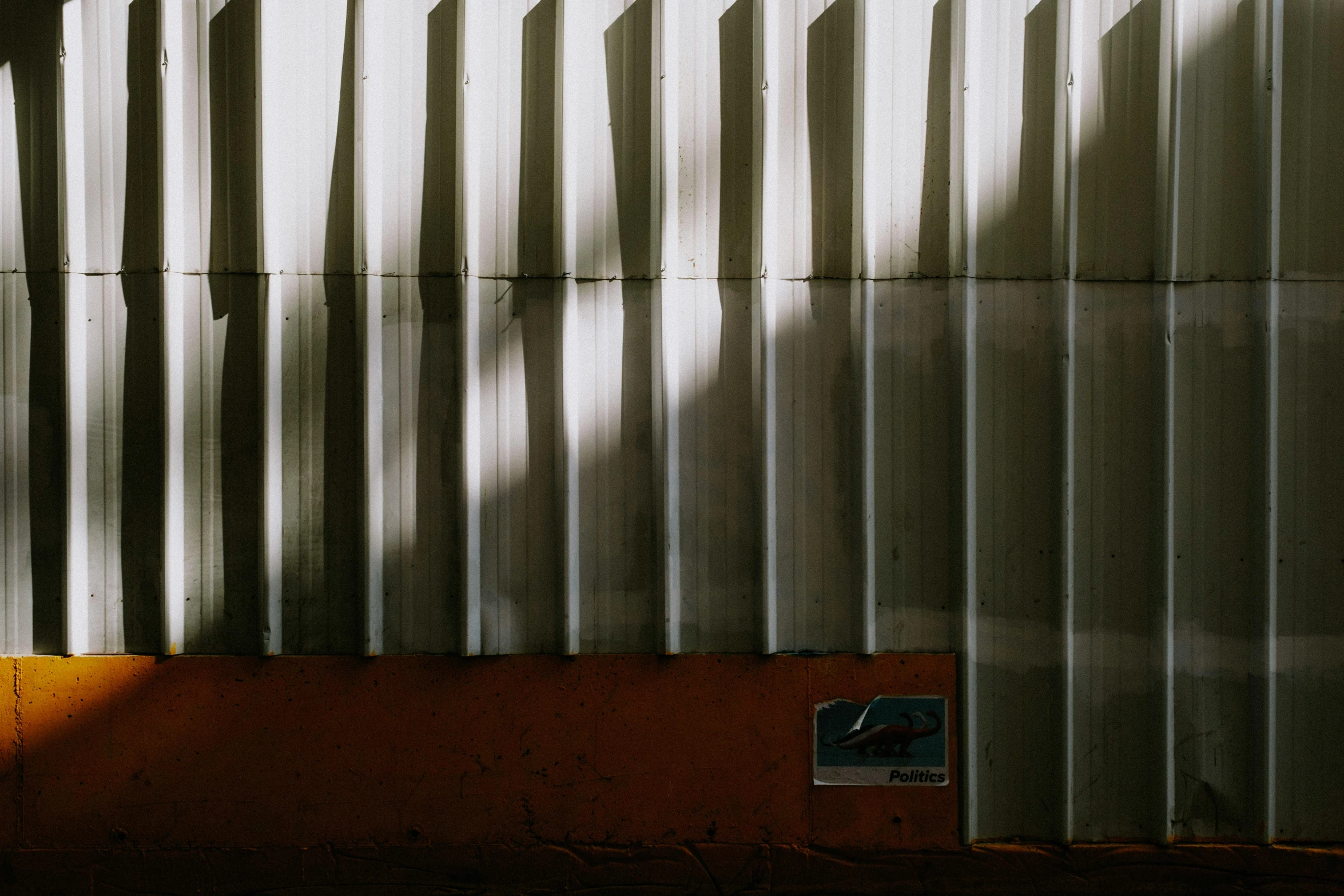 a fire hydrant sitting on the side of a building, inspired by Elsa Bleda, pexels contest winner, postminimalism, soft light through blinds, gray and orange colours, metal panels, in a warehouse