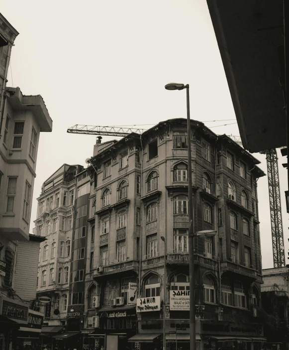 a black and white photo of a city street, by Ismail Acar, pexels contest winner, art nouveau, fallout style istanbul, building facing, 1980s photo, muted and dull colors