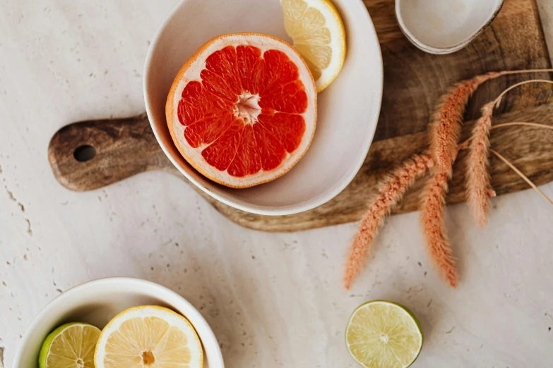 a bowl of fruit sitting on top of a wooden cutting board, by Carey Morris, trending on pexels, holding a drink, sliced grapefruit, exquisite marble details, botanicals