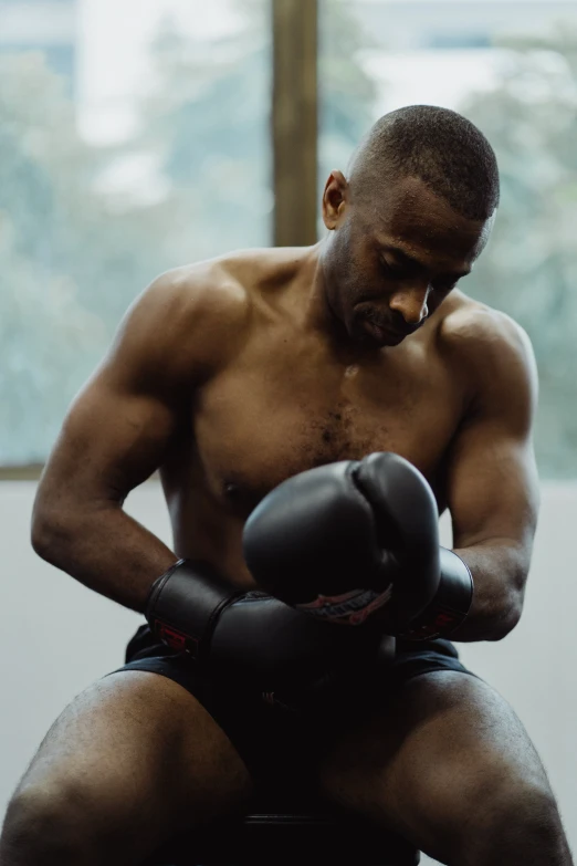 a man that is sitting down with a boxing glove, black man, shirtless, boxing gloves, multiple stories