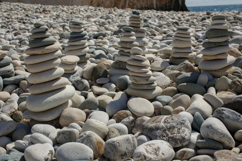 a pile of rocks sitting on top of a beach, inspired by Andy Goldsworthy, unsplash, land art, tall stone spires, costa blanca, paul barson, yin yang