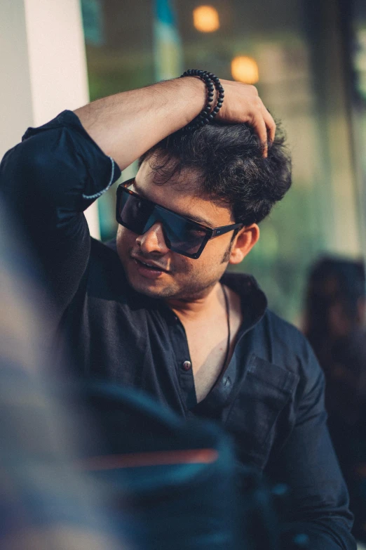 a man wearing sunglasses sitting in front of a store window