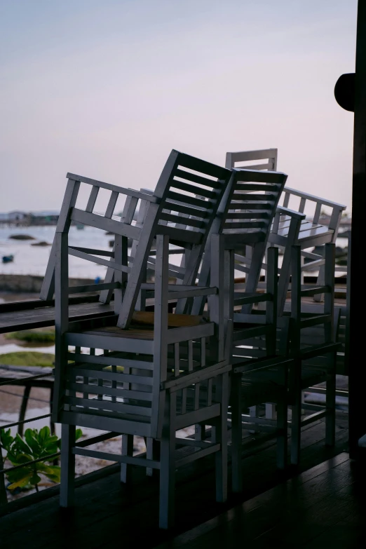 a number of chairs on a porch near a body of water, stacked buildings, sri lanka, sitting at the bar, very windy