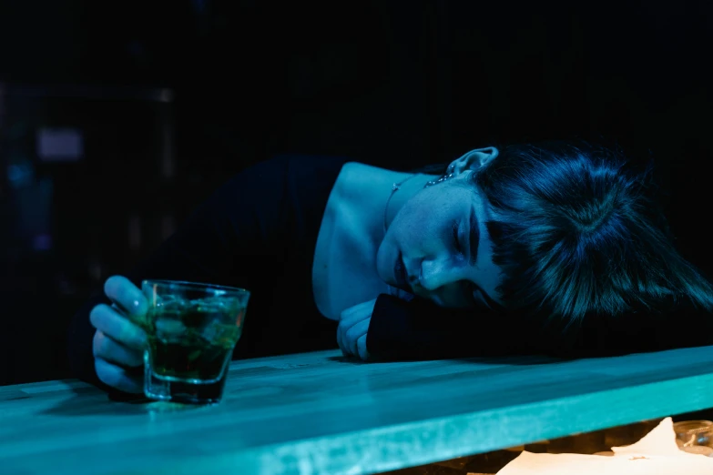 a woman leaning on a bar with a drink in her hand, inspired by Elsa Bleda, pexels, renaissance, distraught, laying down, blue, jesus wasted at a party