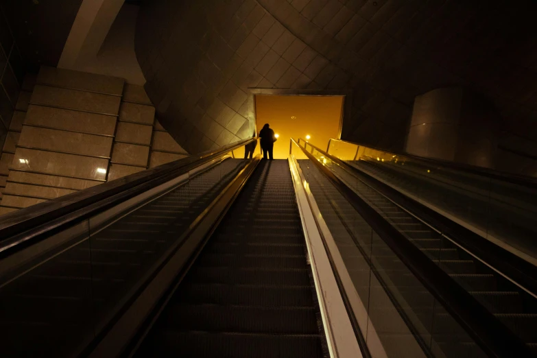 man standing on escalator in dimly lit subway area