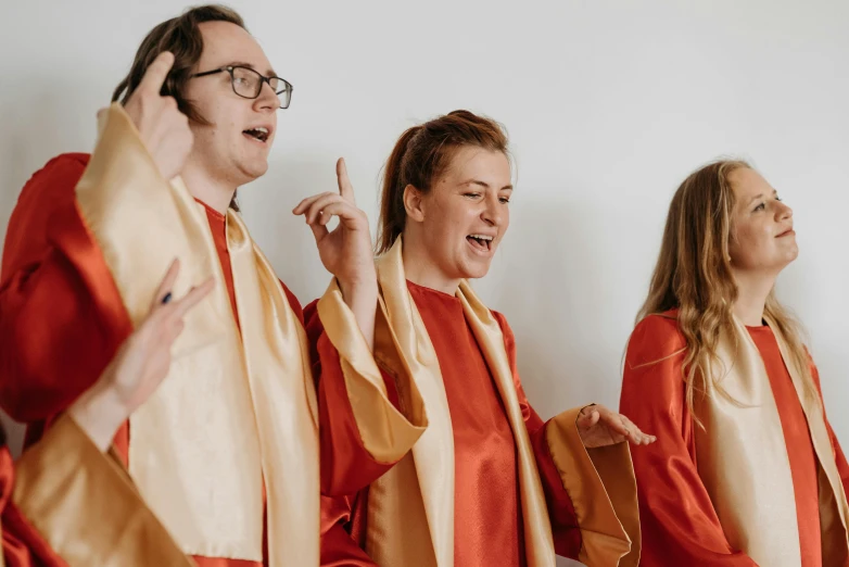 a group of people standing next to each other, an album cover, by Carey Morris, pexels, happening, orange robe, choir, excitement, red robe