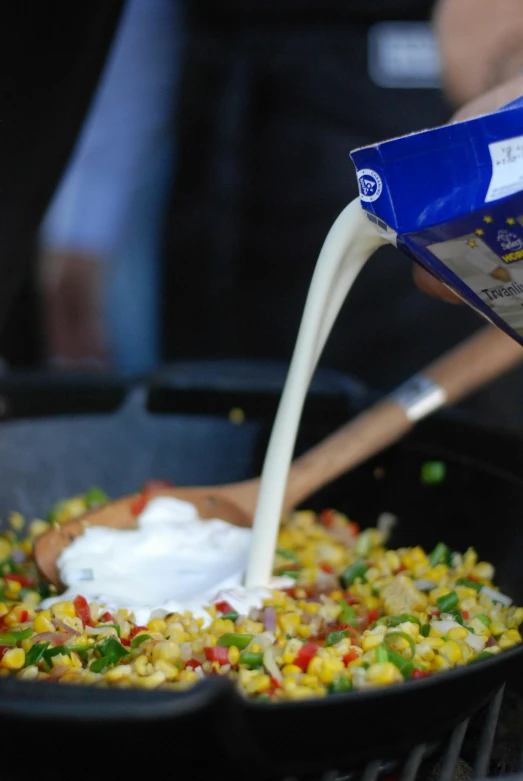 a person pouring milk into a pan filled with food, block party, up-close, corn, napa